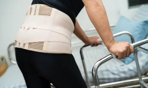 An accident victim on a walker and wearing a brace at a physical therapy session.