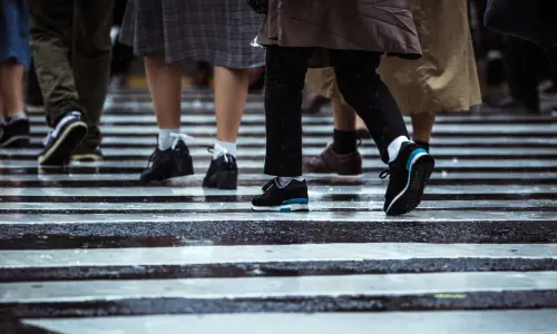 A large crowd of pedestrians at a crosswalk on a rainy day