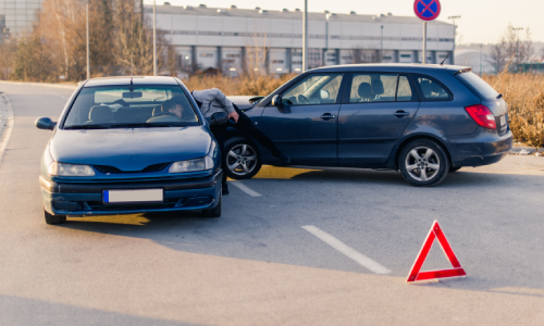 A collision between two cars behind an early warning device and with a driver checking on another.