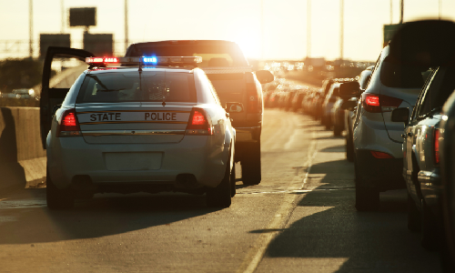 A police car responding to a car accident causing traffic on a flyover.