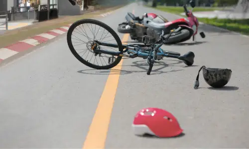 A bicycle fallen over in the middle of the road after a collision with a motorcycle.