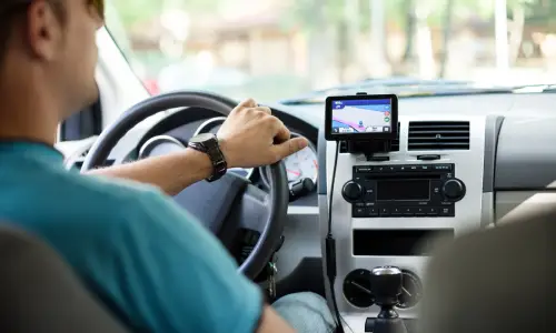 An Uber driver looking at his GPS while driving to pick up a passenger at daytime.