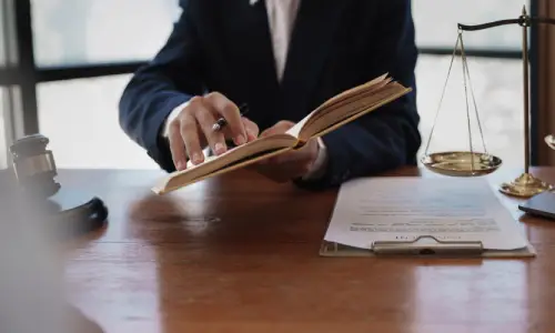 Oakland bicycle accident lawyer studying legal documents at a desk with scales of justice and a gavel, symbolizing dedication to personal injury cases.