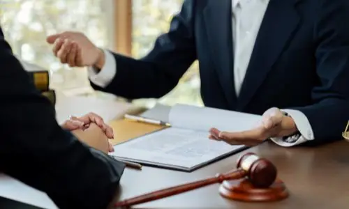 Oakland defective drug lawyer consulting with a client at a desk, with legal documents and a gavel in view, symbolizing advocacy in defective drug cases.