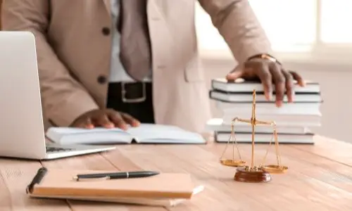 Oakland dog bite lawyer preparing legal materials at a desk, with scales of justice, books, and a notebook, representing commitment to personal injury cases.