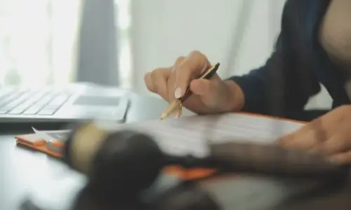 Oakland pedestrian accident lawyer reviewing legal paperwork at a desk with a gavel and laptop, symbolizing commitment to representing injured pedestrians.