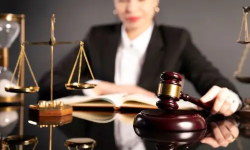 Oakland personal injury lawyer reviewing legal documents at a desk with scales of justice, gavel, and hourglass in the foreground.