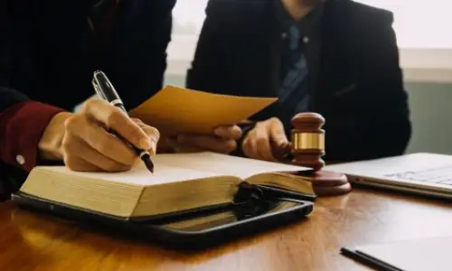 Oakland slip and fall lawyer taking notes and reviewing case files with a colleague at a desk, with a gavel and legal documents in view, symbolizing expertise in personal injury cases.