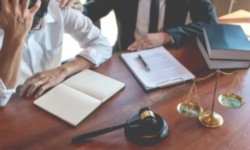 Oakland traumatic brain injury lawyer providing support to a distressed client, with legal documents, scales of justice, and a gavel on the desk, symbolizing advocacy in severe injury cases.