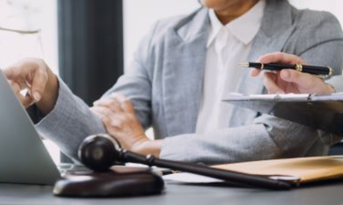 San Diego bicycle accident lawyer discussing case with client at desk, with gavel, scales of justice, and legal documents