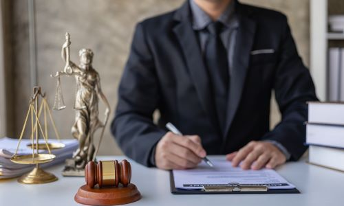 San Diego defective drug lawyer reviewing legal documents at desk with Lady Justice statue, gavel, and scales