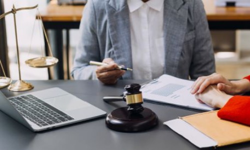 San Diego motorcycle accident lawyer consulting with a client, legal documents and gavel on the desk, with a laptop in the background.