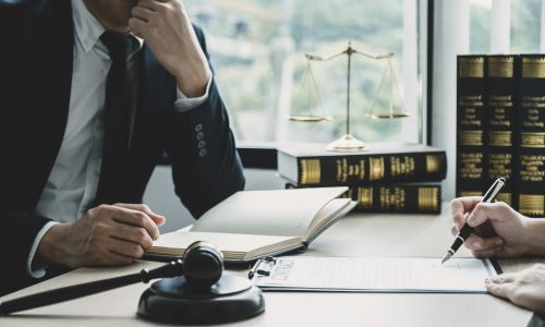 San Diego pedestrian accident lawyer consulting with client, with gavel, legal books, and scales of justice on desk