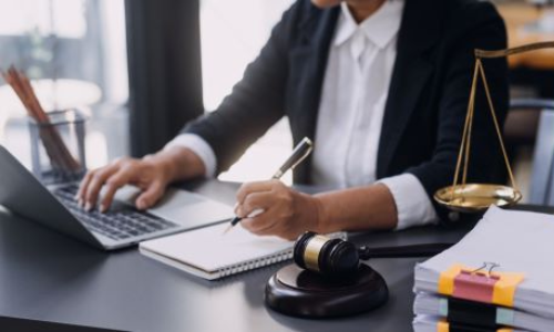 San Diego traumatic brain injury lawyer working at desk with laptop, legal documents, gavel, and scales of justice