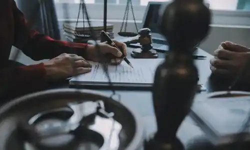 San Diego slip, trip, and fall lawyer reviewing documents with client, with gavel, scales of justice, and handcuffs on desk