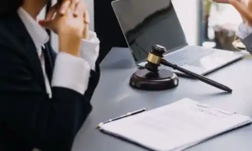 San Diego truck accident attorney reviewing paperwork with a client, pointing at a document in a law office with a gavel and scales.