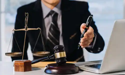 San Diego Uber accident lawyer discussing case with client, with gavel, scales of justice, and laptop on desk